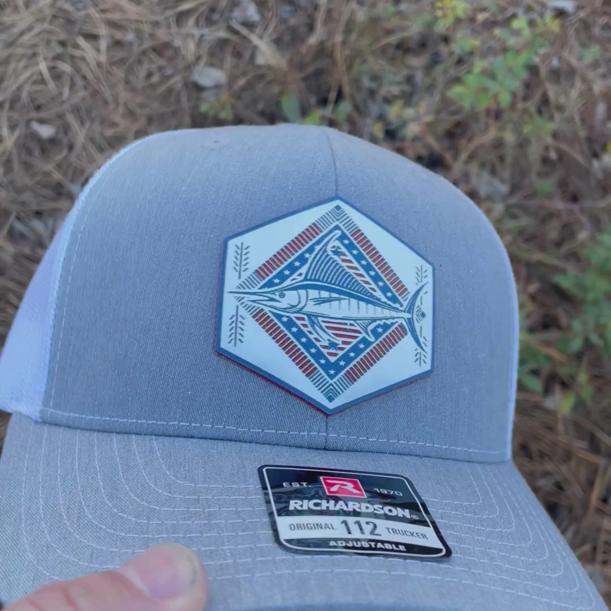 Video of a heather gray Rustic Pines Outfitters trucker hat featuring a Blue Marlin in a Santa Fe design style.